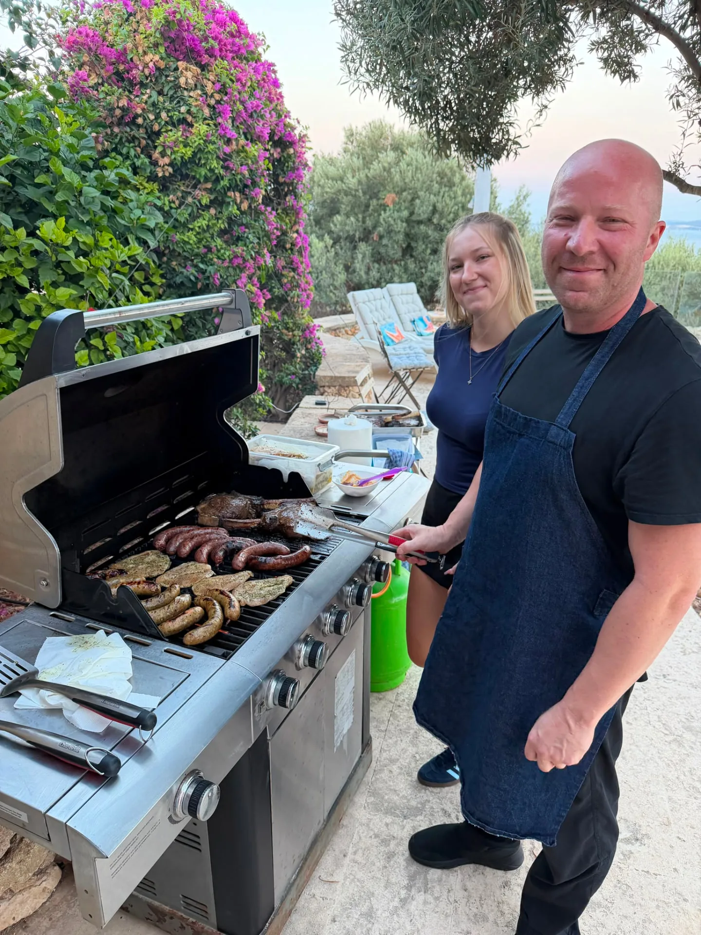 Chef Laszlo grilling steak and artisan sausages on a terrace at sunset in Gozo